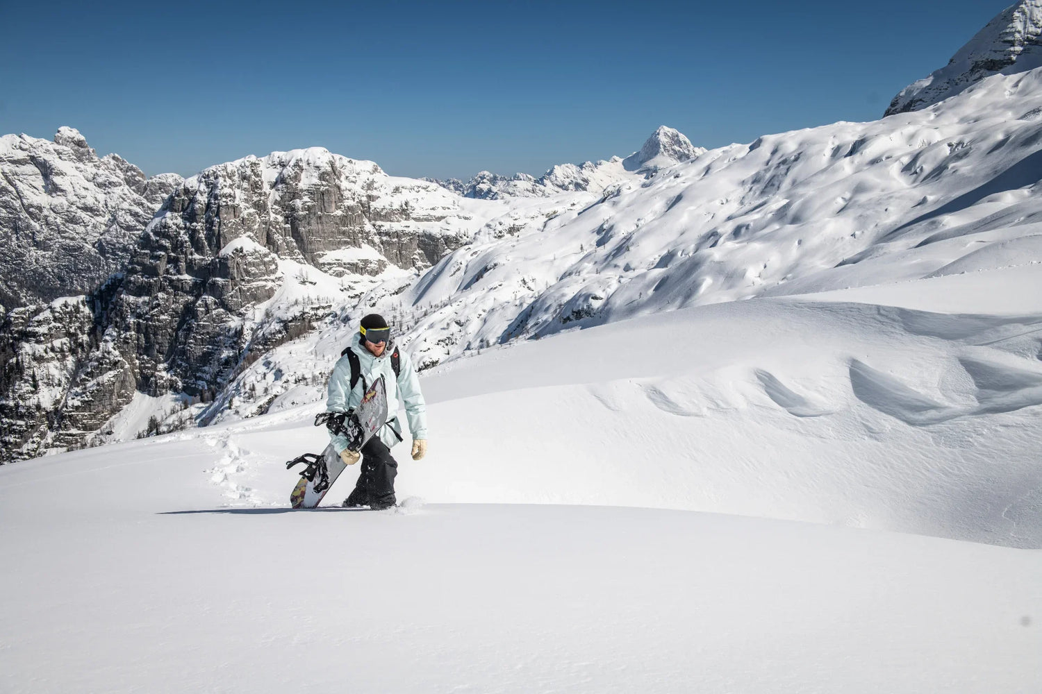 Person snowshoeing through a snowy landscape with mountains in the background